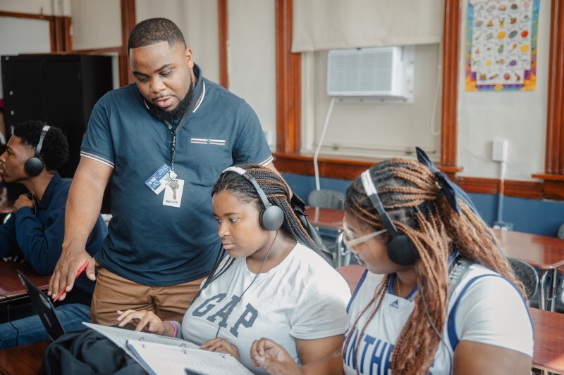 teacher with 2 middle school students reviewing work