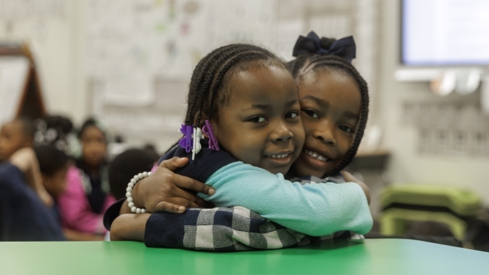 elementary students hugging in classroom