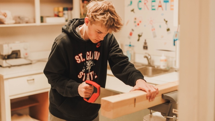 student sawing wood