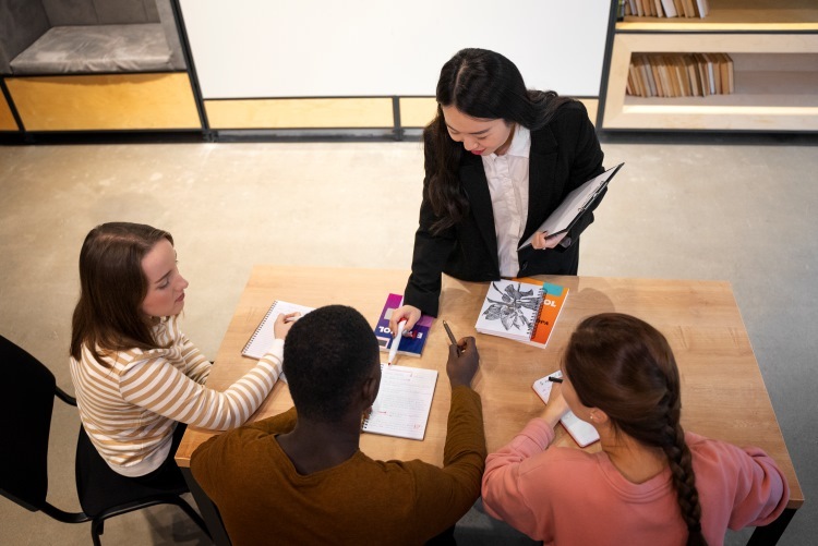 teacher working with small group of high school students at small table