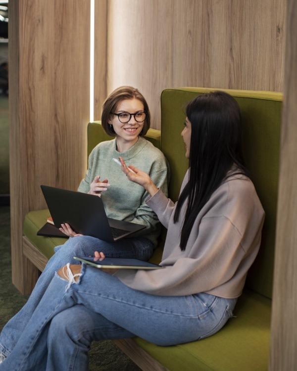 two students with laptops in small nook