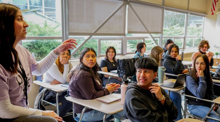 teacher alongside students in desks in rows