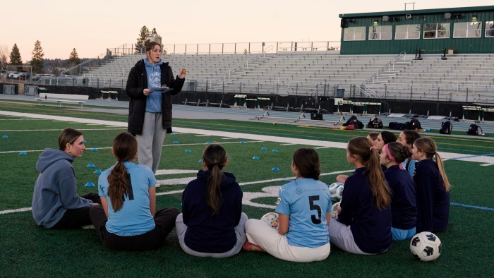 student athletes huddle with soccer coach