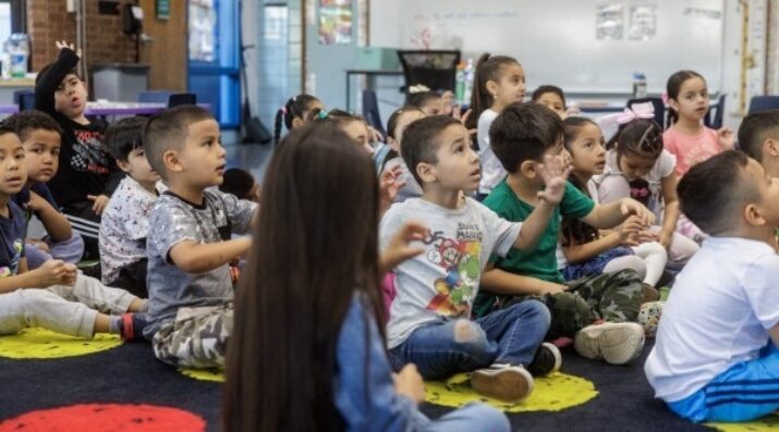 large group of elementary students sitting on an area rug
