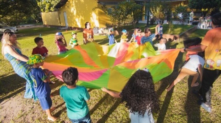 children joyfully playing with a colorful parachute at an outdoor summer camp