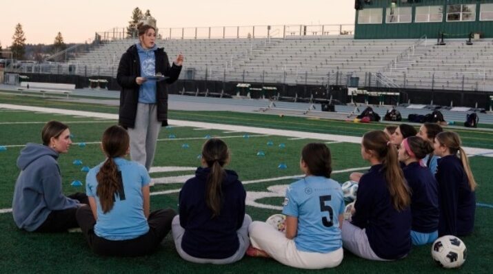 students huddle with soccer coach
