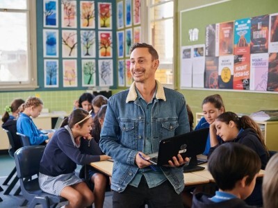 Teacher holding laptop in classroom