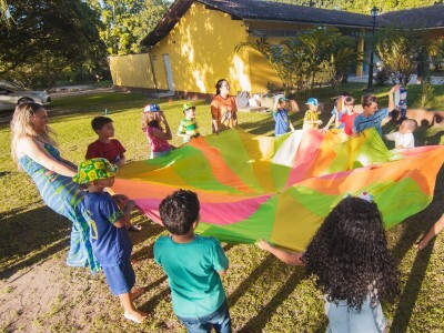 children playing with a colorful parachute at an outdoor summer camp