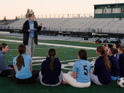 students huddle with soccer coach